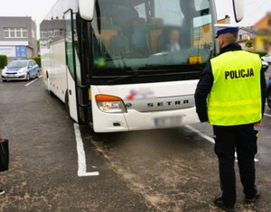 policjant w mundurze stoi przy kontrolowanym autokarze
