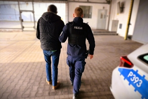 policjant prowadzi zatrzymanego