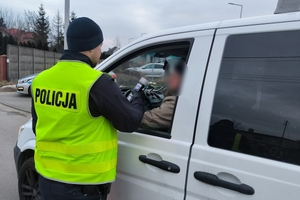 umundurowany policjant bada trzeźwość kierowcy, który siedzi w samochodzie