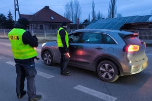umundurowany policjant bada trzeźwość kierowcy, który siedzi w samochodzie