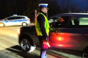 umundurowany policjant sprawdza stan trzeźwości kierowcy samochodu