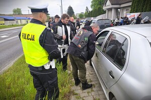 Policjanci i motocykliści podczas rozmowy z kierowcą na temat bezpieczeństwa w ruchu drogowym.