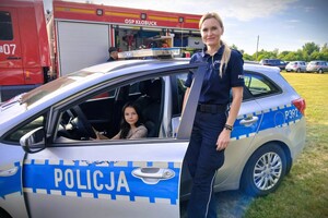 policjantka w mundurze na pikniku, obok policyjny radiowóz i sprzęt wykorzystywany w codziennej służbie