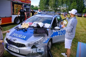 policjantka w mundurze na pikniku, obok policyjny radiowóz i sprzęt wykorzystywany w codziennej służbie