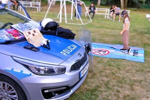 policjantka w mundurze na pikniku, obok policyjny radiowóz i sprzęt wykorzystywany w codziennej służbie