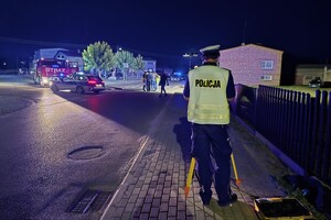 Umundurowany policjant wykonuje czynności na miejscu wypadku.