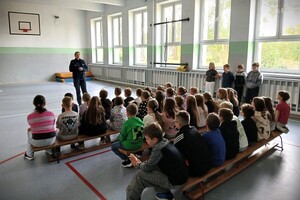 policjantka w mundurze prowadzi pogadanki przed grupą dzieci i młodzieży